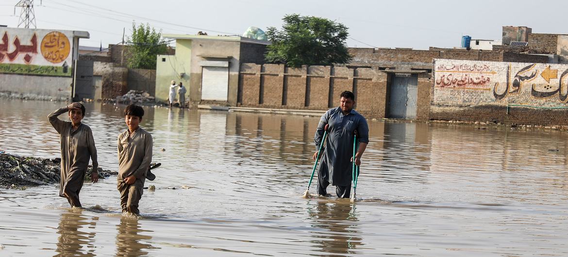 Des enfants et un homme dans des rues inondées de Nowshera Kalan, au Pakistan.